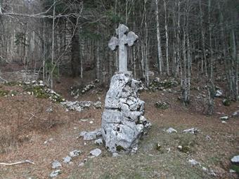 Con qualche saliscendi fra miseri ruderi di ricoveri arriviamo in breve ai resti di un cimitero, dove campeggia un'imponente croce in cemento costruita nel lontano maggio 1916.